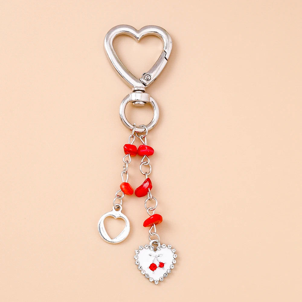 Silver heart-shaped keychain with a chain and red beads, featuring a small heart charm.