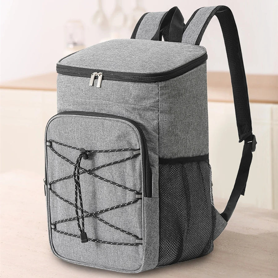 A gray insulated lunch backpack with a waterproof oxford shell and black strap is shown on a light surface.
