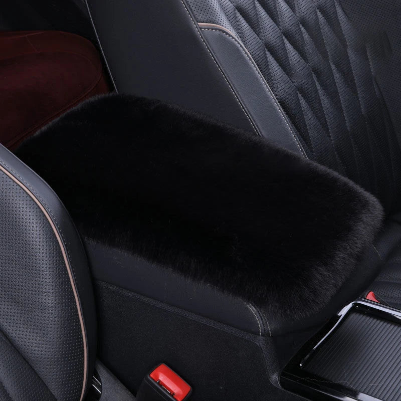 A black plush car armrest cushion set with quilted leather upholstery and a red accent.