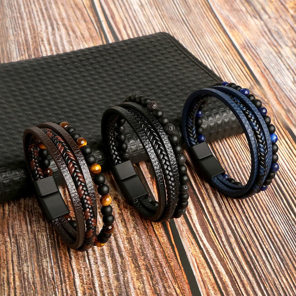 A collection of men's multi-layer leather bracelets featuring tiger eye beads displayed on a dark surface.