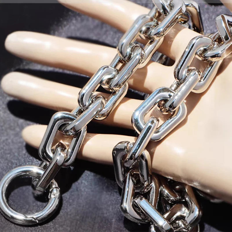 Correa de bolso de acrílico plateado con cadena, enlazada alrededor de un dedo para escala.