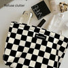 A black and white checkered cosmetic storage bag next to various beauty products like perfume and skincare.