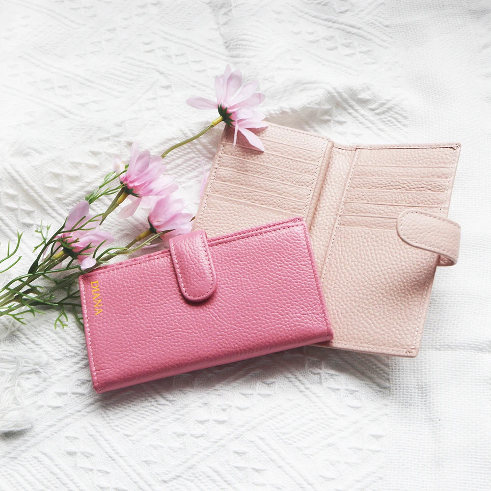 A pink leather card holder and coin purse resting on a white textured fabric with pink flowers.