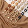 A collection of acrylic handbag strap chains in various shades of amber, beige, and blue displayed on a brown fabric.