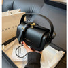 A black textured leather shoulder bag is shown being held inside a box with a thank you note.
