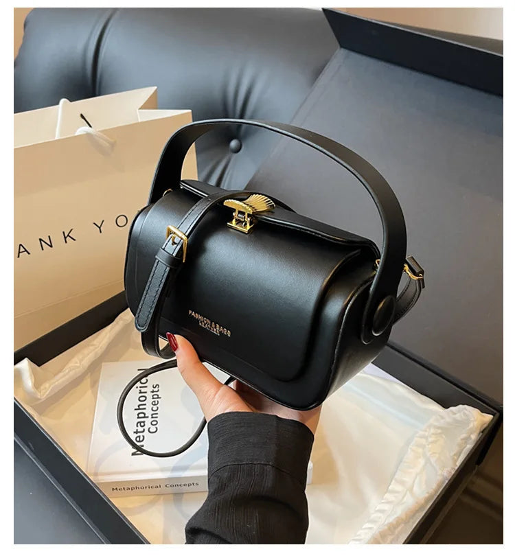 A black textured leather shoulder bag is shown being held inside a box with a thank you note.