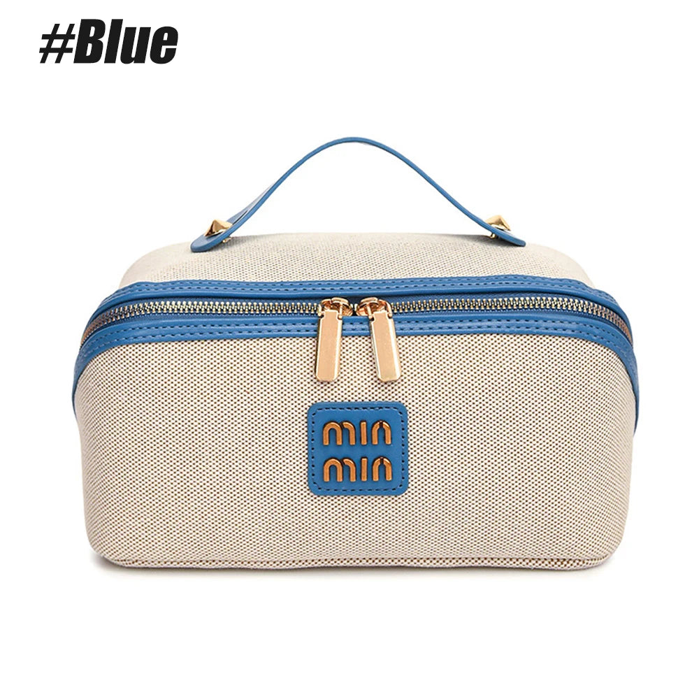 A beige and blue large capacity travel toiletry bag with a handle and zipper closure.