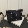 Black embroidered makeup pouch with a zipper resting on a white box.