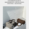 A brown leopard print riveted shoulder bag resting on a gray concrete surface.