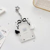 Clear acrylic photocard holder with a black bow and silver charm on a white background