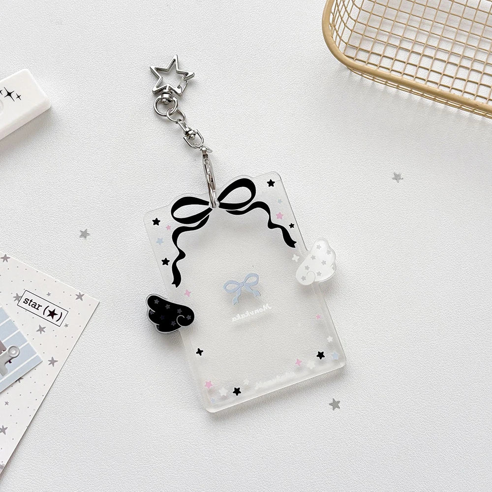 Clear acrylic photocard holder with a black bow and silver charm on a white background