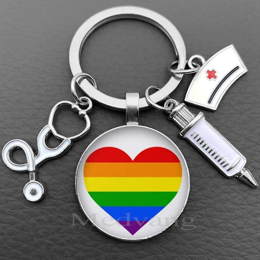 Silver keychain featuring a heart design with the Pride rainbow flag and a medical syringe charm
