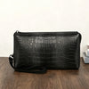 Clutch de estampado de cocodrilo negro sobre una superficie de madera oscura.