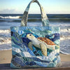 A quilted canvas tote bag featuring a colorful sea turtle design on a blue and green background.