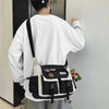 Una persona vista desde atrás, usando una camisa blanca de manga larga y un bolso cruz negro de nylon con detalles claros.