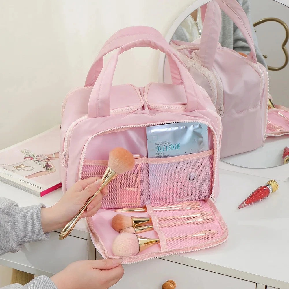 A pink multipocket travel toiletry bag is shown open, revealing various makeup brushes and tools.