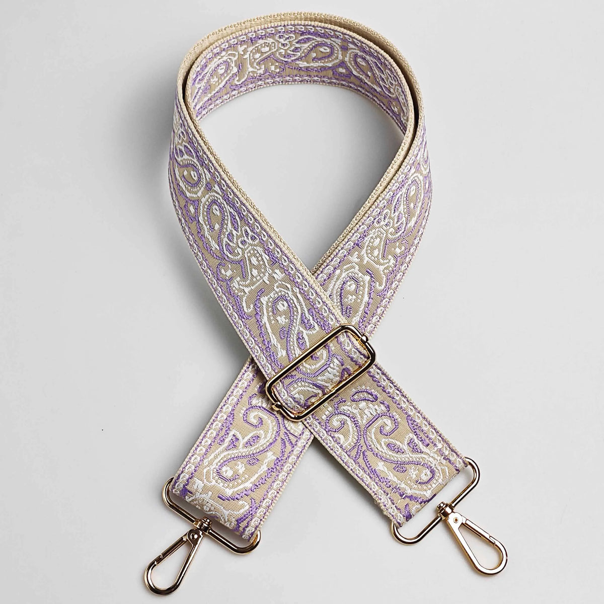 Correa ajustable de bolso cruz ancho beige y morado con herrajes dorados.