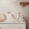 A white flannel diaper caddy organizer with a looped white trim is displayed on a light-colored dresser.
