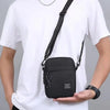 A black minimalist nylon crossbody bag worn by a man in a white t-shirt.