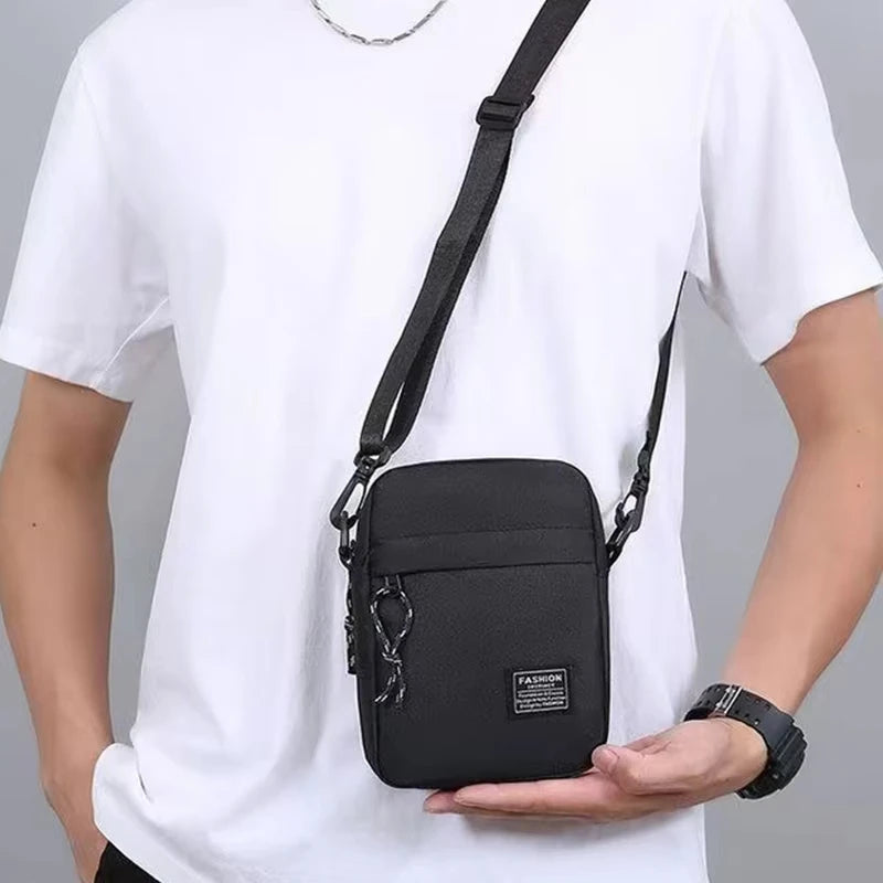 A black minimalist nylon crossbody bag worn by a man in a white t-shirt.
