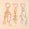 Gold and silver heart-shaped keychains featuring seashells, starfish, and pearl accents.