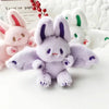 A purple bat bunny plush toy with soft wings and pink accents is displayed on a white surface.