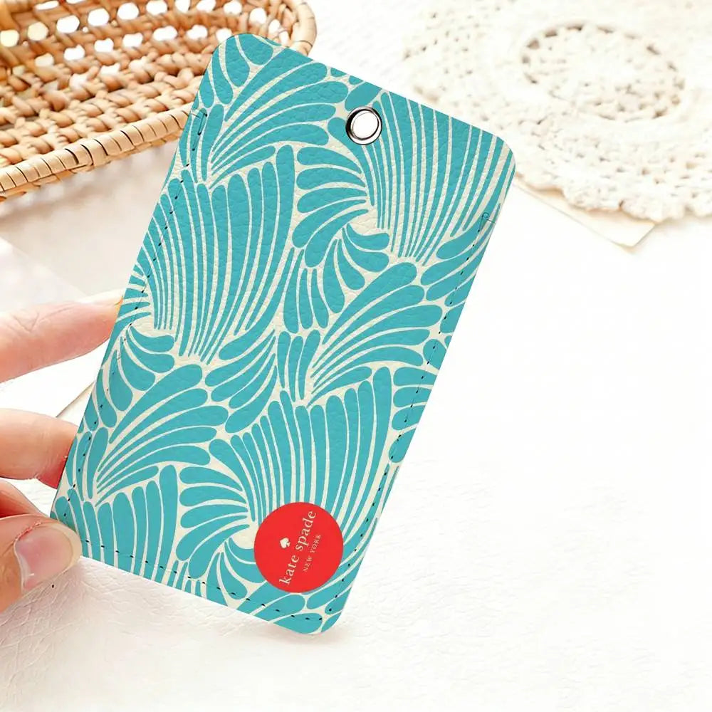 A teal patterned card holder featuring a swirling leaf design is held against a white background.