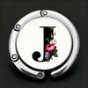 Silver foldable letter hanger hook with a decorative floral design.