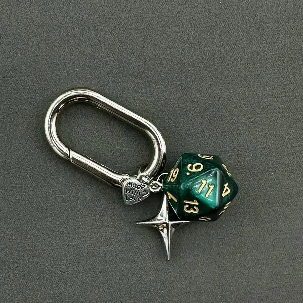 A silver keychain featuring a green resin die with the number 13 and a star charm.