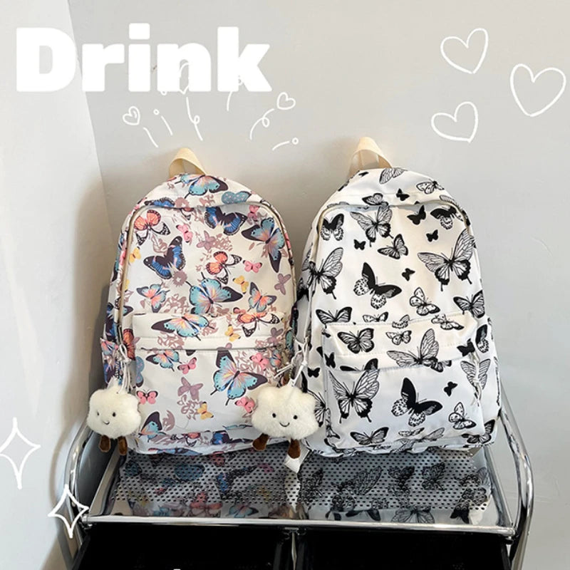 A white backpack featuring a colorful butterfly pattern is displayed on a shelf.