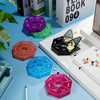 A collection of colorful 7-day weekly pill organizers in various shapes and colors arranged on a blue surface.