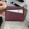 Porte-cartes en cuir marron avec une carte gravée blanche, tenue par une main.