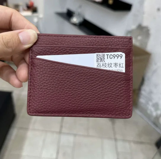 Porte-cartes en cuir marron avec une carte gravée blanche, tenue par une main.