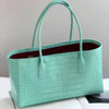 A mint green crocodile embossed leather tote bag with a handle and magnetic closure.