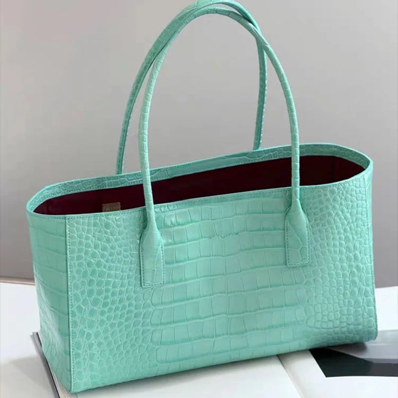 A mint green crocodile embossed leather tote bag with a handle and magnetic closure.