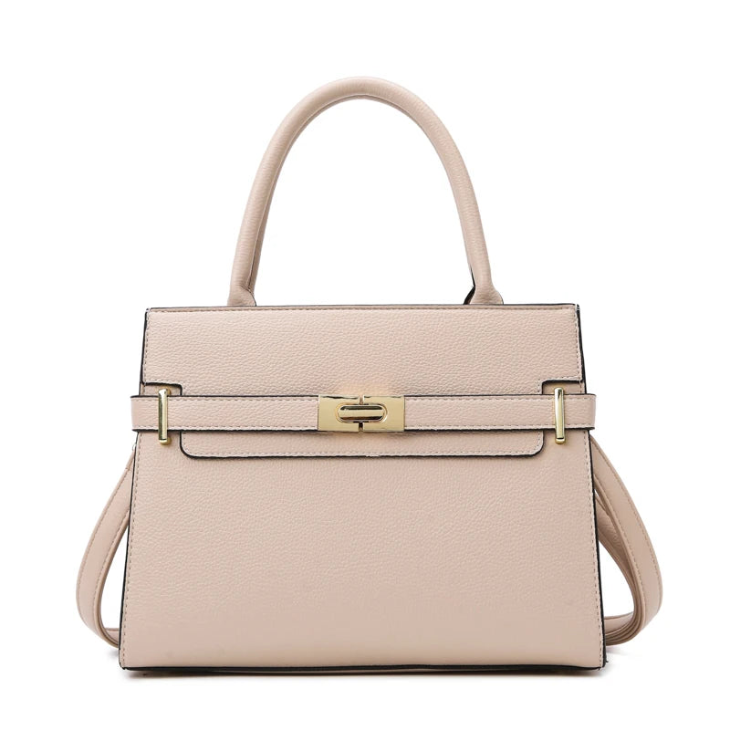 A light pink leather handbag with a tan handle and gold hardware.