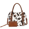 A brown leather tote bag with a white cow print pattern and matching leather trim.