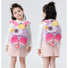 A young girl is shown holding a purple and pink cartoon animal plush backpack for kids.