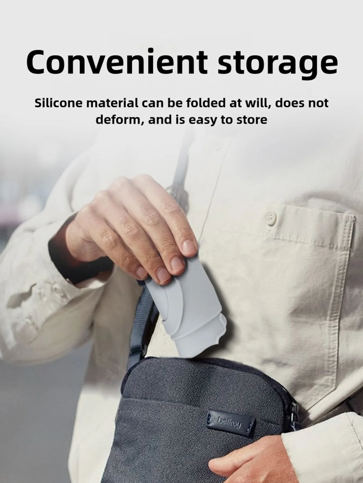 A person is holding a gray silicone cup holder attached to a bag, demonstrating its convenient storage.