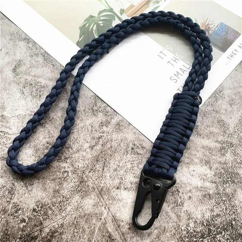 A dark blue hand-woven nylon lanyard with a metal hook is displayed on a gray textured surface.