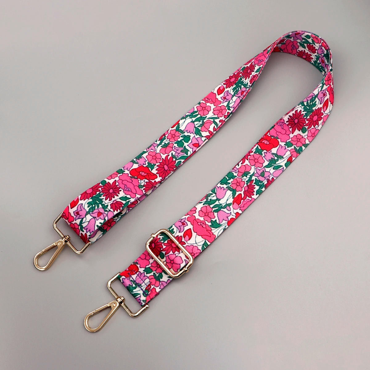 A pink and green floral pattern adjustable strap for a crossbody bag.
