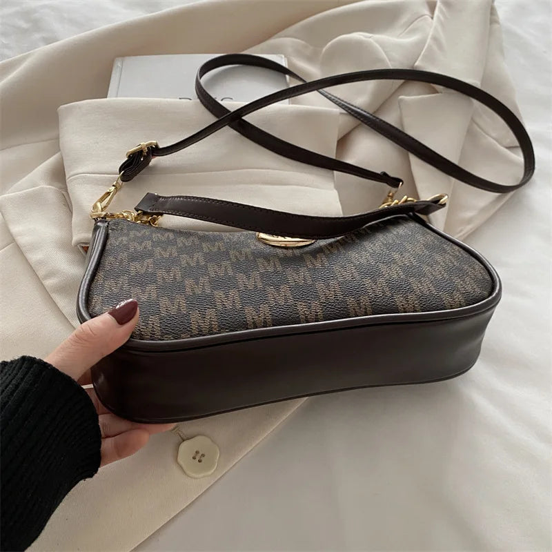 Bolso cruz marrón con cadena dorada, sobre fondo blanco.