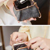 A hand holds a retro kiss lock coin purse in gray leather with a gold chain keychain.