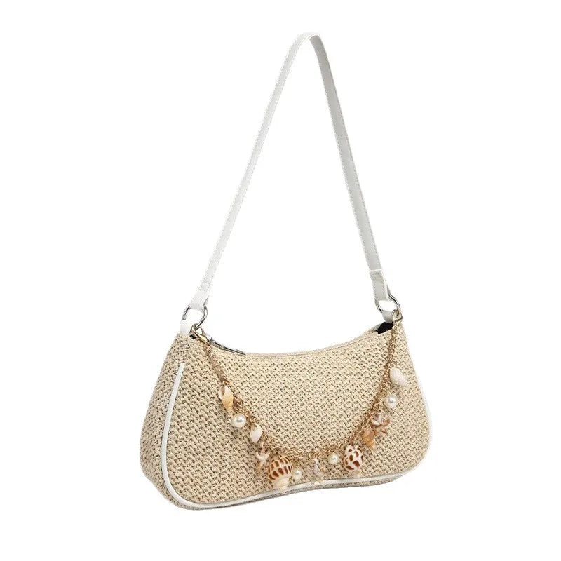 A beige straw shoulder bag featuring delicate ocean-themed charms and a white strap.