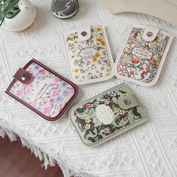 A collection of elegant floral PU card wallets in various patterns resting on a white knitted surface.