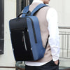 A person wearing a light sweater is carrying a dark blue laptop backpack outdoors.