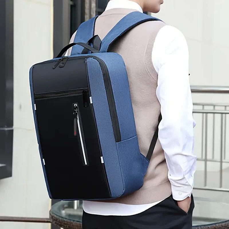 A person wearing a light sweater is carrying a dark blue laptop backpack outdoors.