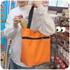 A person holds an orange shopping bag in front of a white long-sleeved shirt.