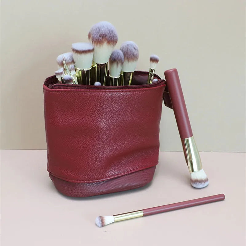 A maroon stretchable PU leather makeup brush storage case filled with various makeup brushes.