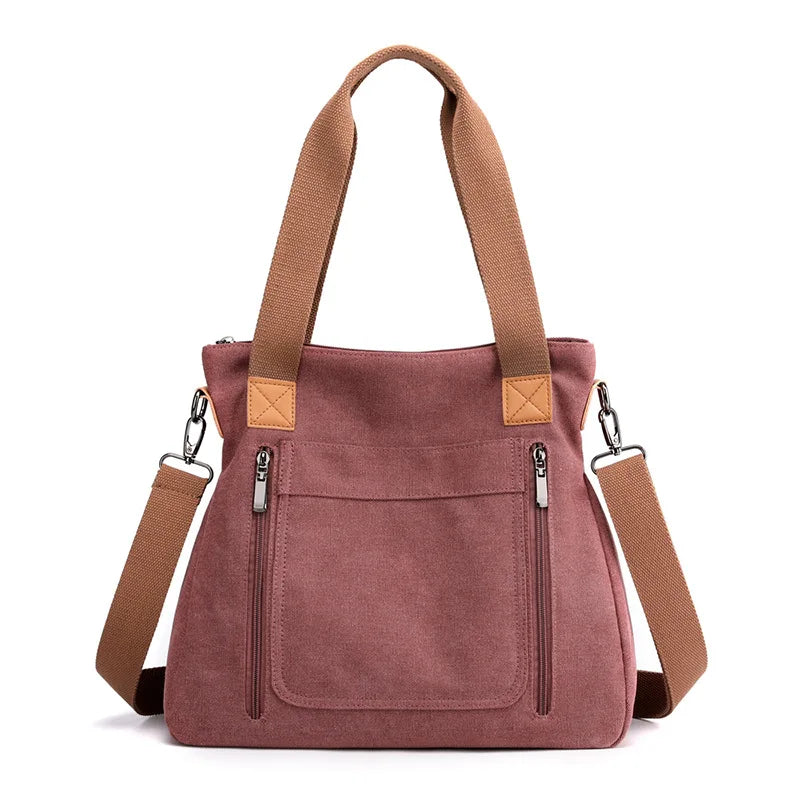 A mauve canvas tote bag with tan straps and zipper details.